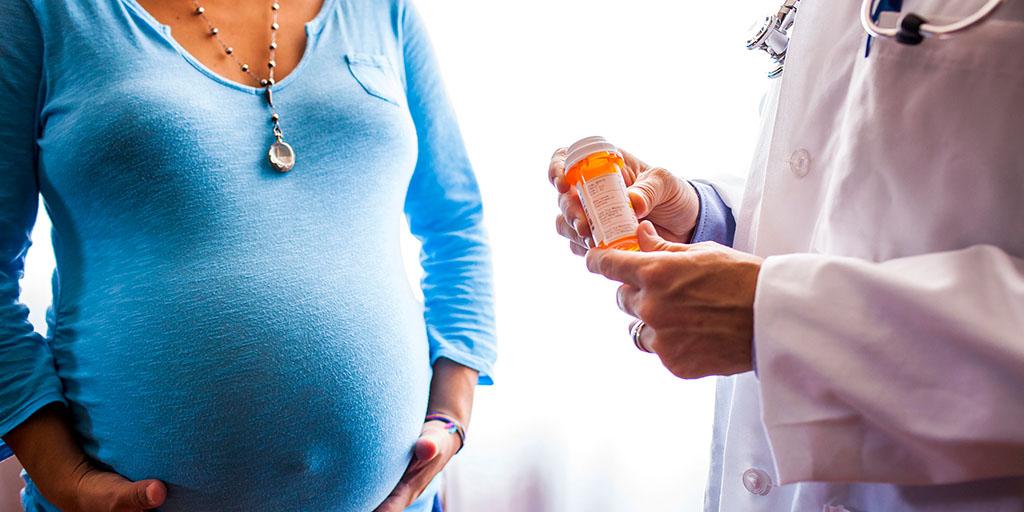 a doctor gives a pregnant woman prescription medication