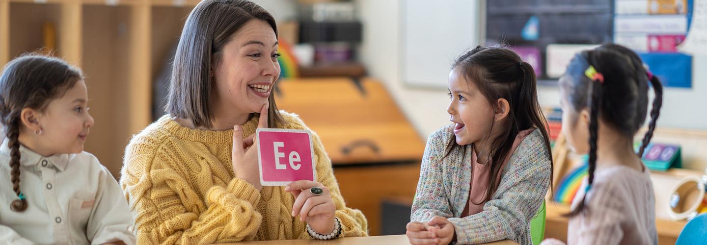 a teacher helps her class learn letters