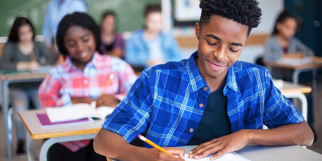 a young man works in a notebook in class