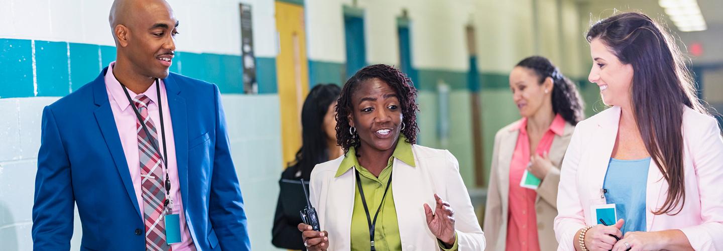 a group of teachers walk down the hallway of a school