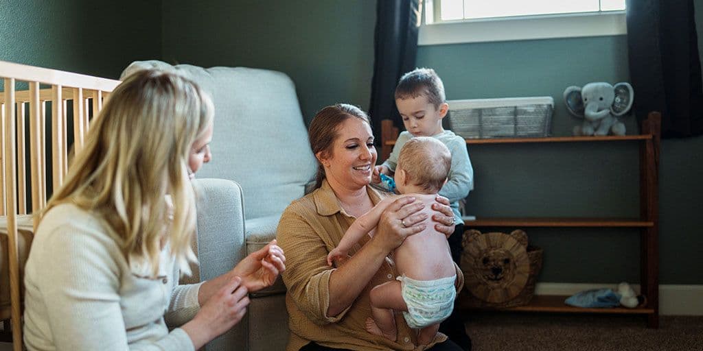 a nurse helps a mother with a young baby