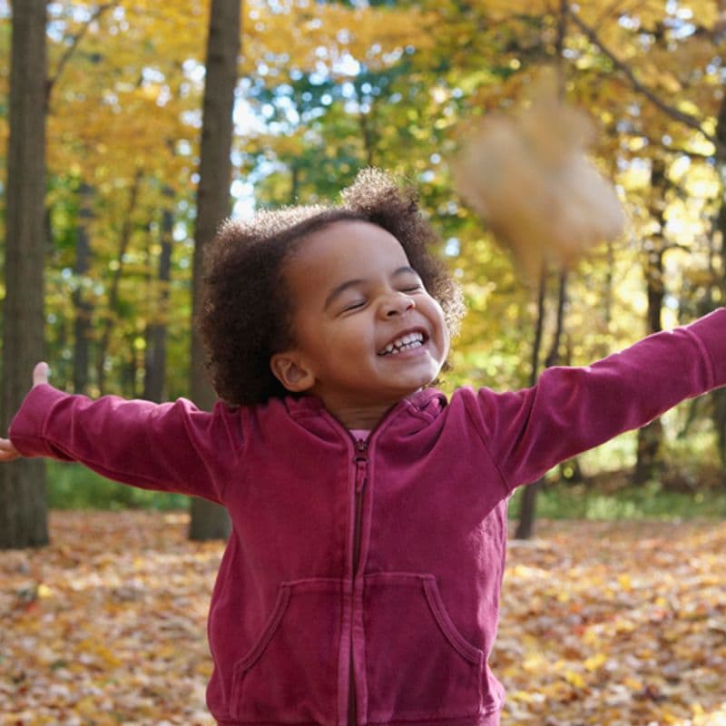 African American girl playing in autumn leaves