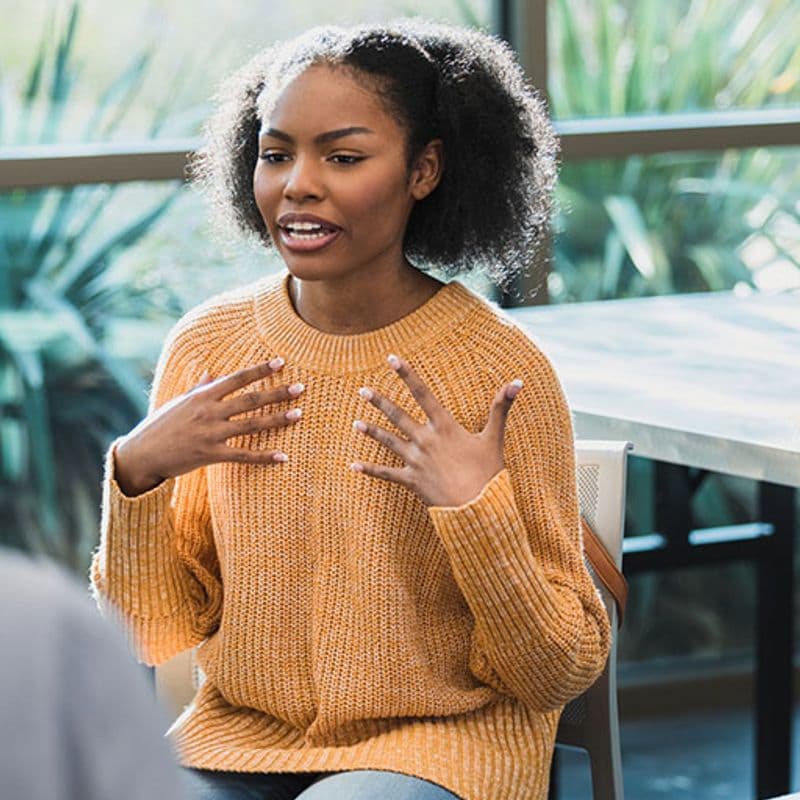 a young woman talks to peers in a group setting